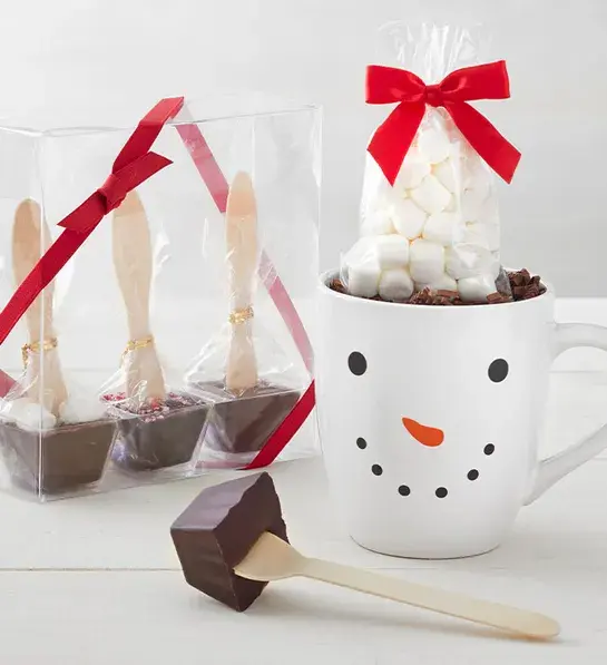 Christmas gifts for him with several chocolate covered spoons and a mug with a snowman's face on it.