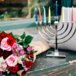 A photo of facts about Hanukkah with a menorah and a bouquet of flowers on a bench