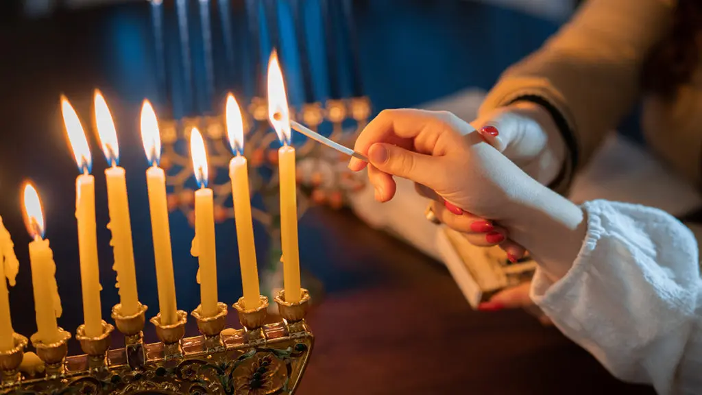 Facts about Hanukkah. Hand lighting menorah