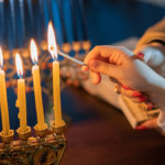This is a photo of facts about hanukkah. Hand lighting menorah