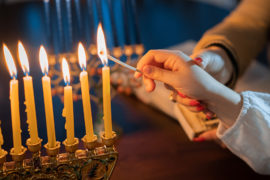Facts about Hanukkah. Hand lighting menorah