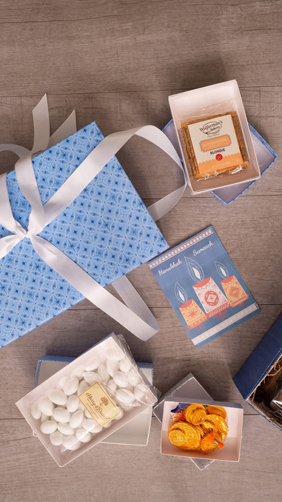 A photo of facts about Hanukkah with a wrapped present, two cards, and some dried fruit surrounding it