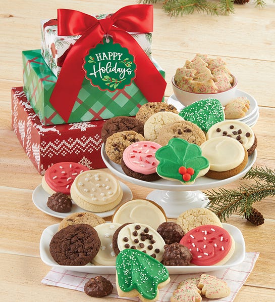 A photo of gifts under $50 with three plates full of cookies and a stack of holiday decorated boxes in the background.