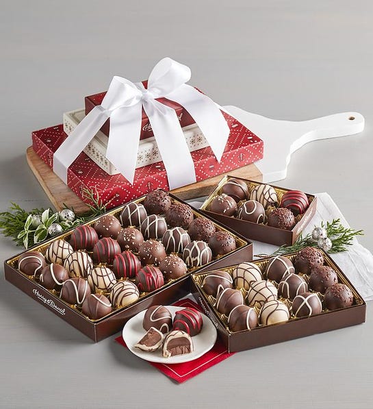 A photo of gifts under $50 with three open boxes of truffles and a stack of three boxes tied with a bow in the background.