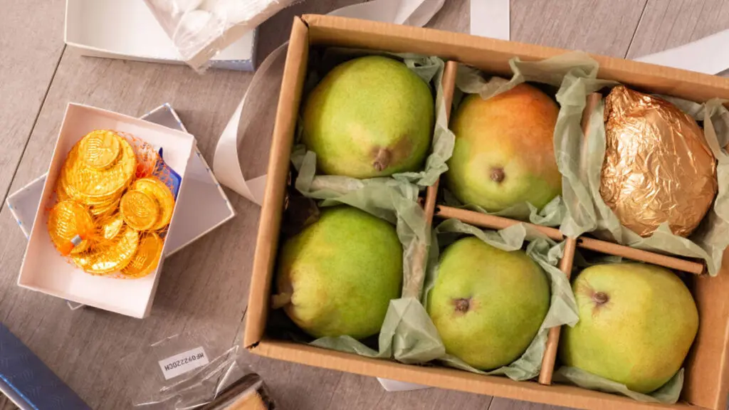 Hanukkah traditions with a box of pears next to a bag of golden wrapped chocolate coins.