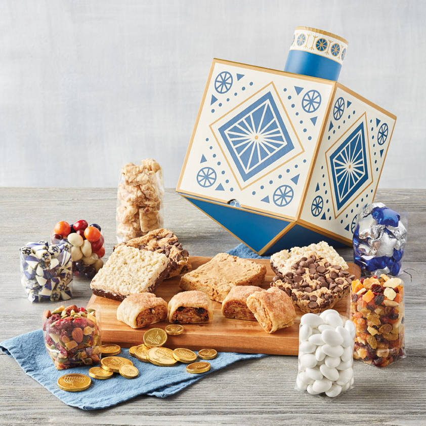 Hanukkah traditions with a large dreidel shaped box full of treats surrounded by Hanukkah sweets and snacks.