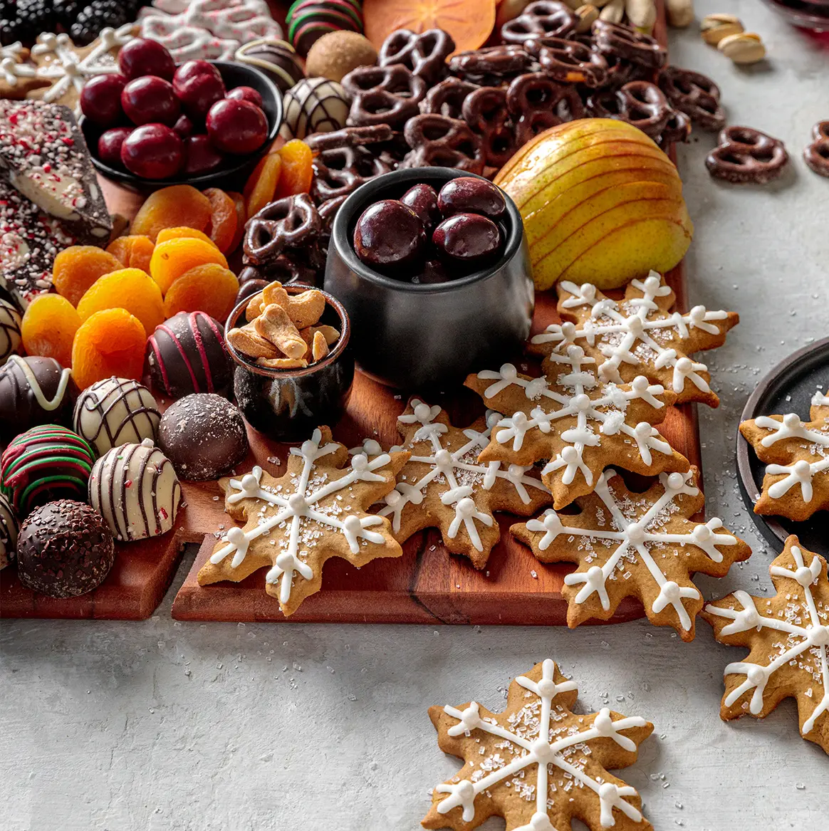 A photo of a dessert board with ginger bread cookies, fruit, nuts and chocolate