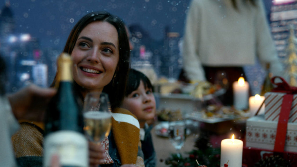 A photo of a holiday party with a woman smiling at someone outside of the camera angle while she holds up a glass of wine.