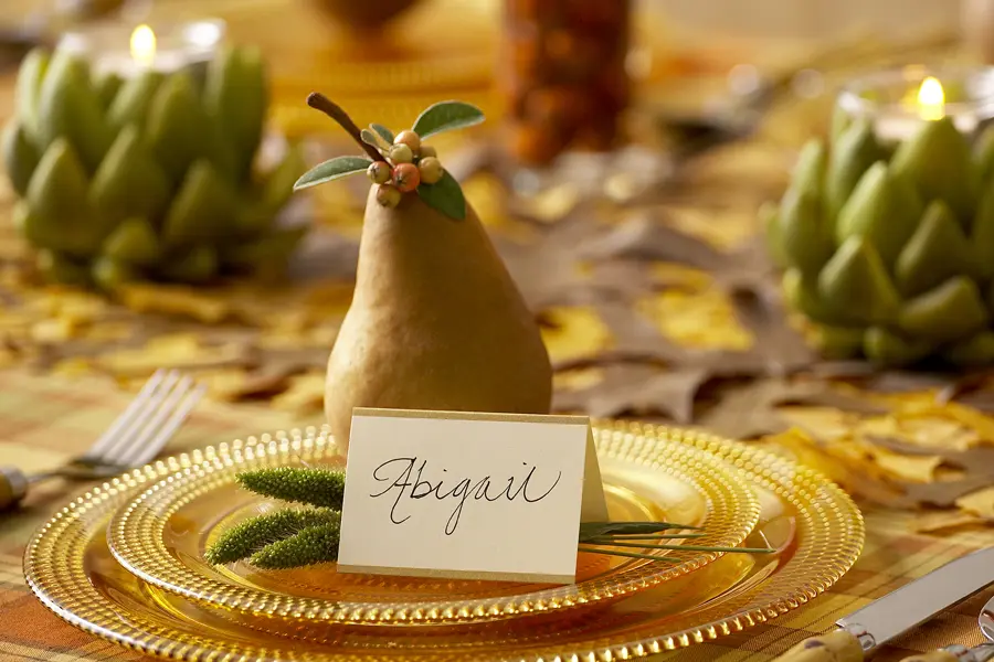 A photo of a pear tablescape with a pear on a gold plate with a name tag