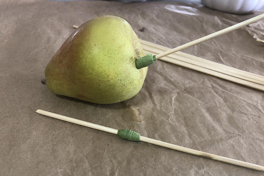 A photo of a pear tablescape with a pear being skewered by a stick