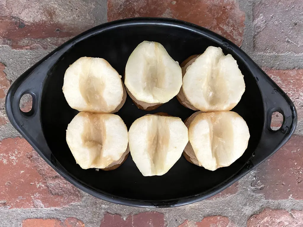 A photo of roasted pears recipe with three pears in a bowl that have been sliced in half and cored