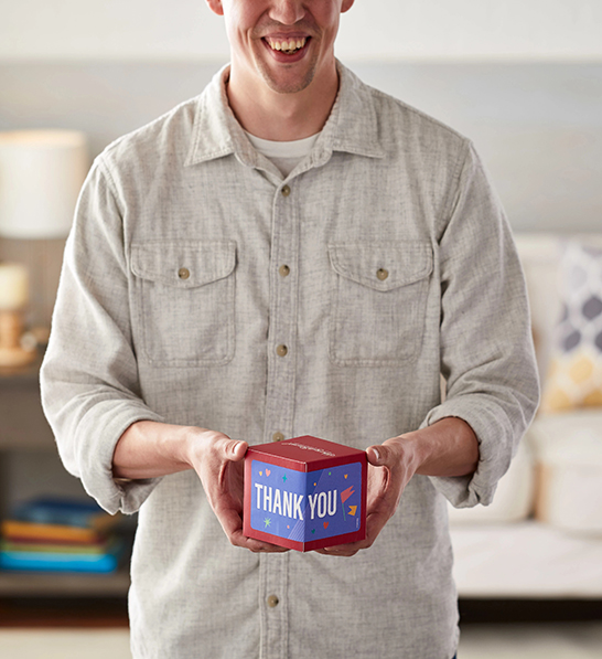 A photo of thanksgiving host gifts with someone holding out a box that says thank you