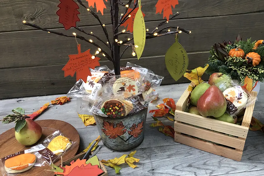 A photo of thanksgiving tree surrounded by cookies and fruit on a table