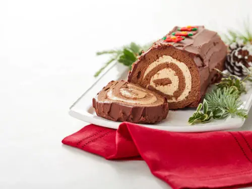 A photo of a bûche de Noël on a plate next to a red napkin