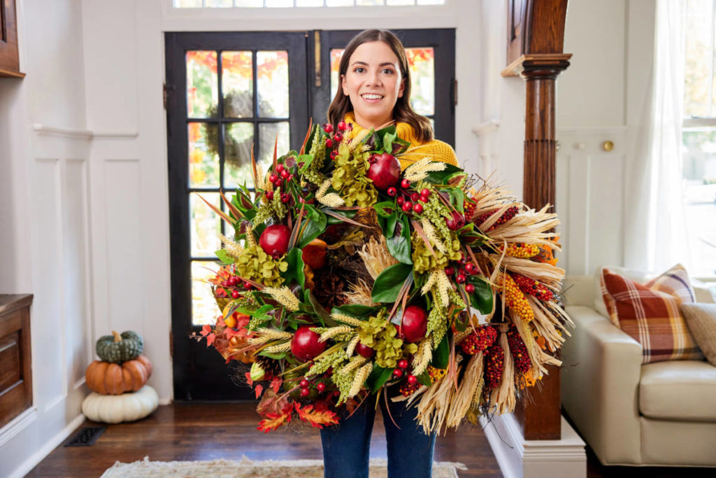 Winter solstice wreath held by a woman smiling at the camera.