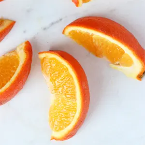 A photo of how to cut an orange with wedges of oranges arranged in a circle. 