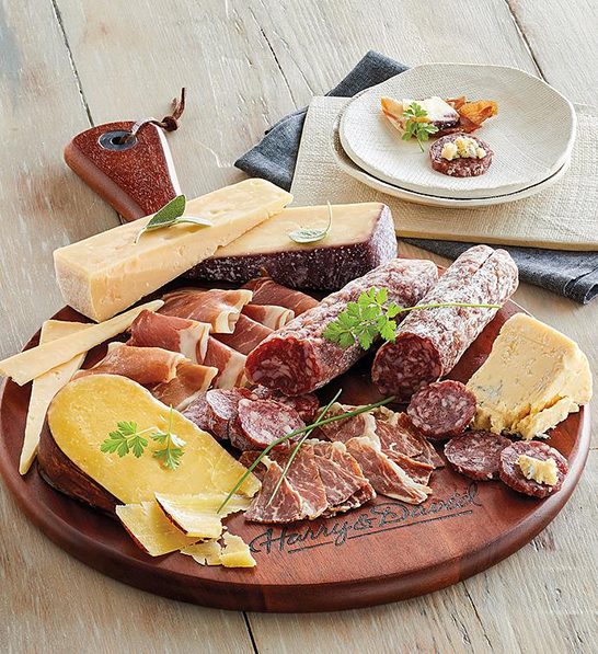 A photo of corporate gifting for the new year with a cutting board holding several different kinds of cheese and meat.