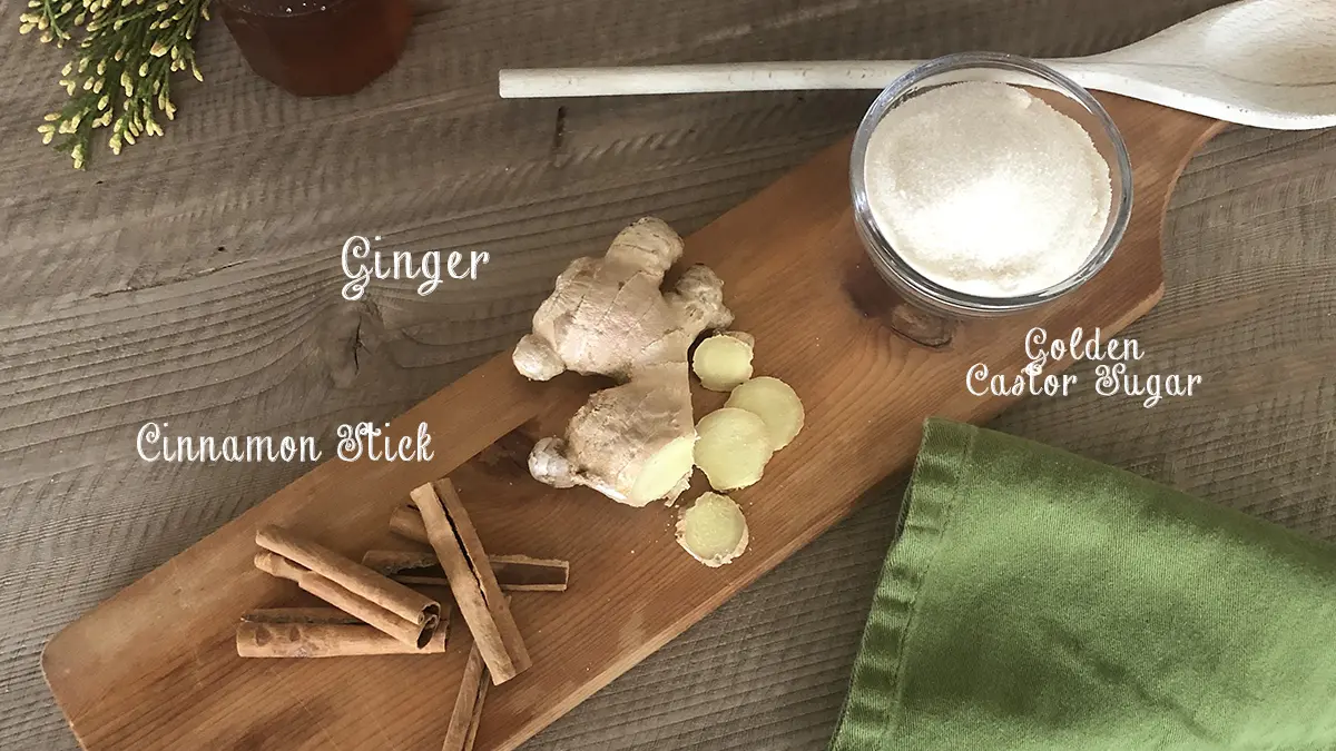 A photo of a craft cocktail with the ingredients lied out on a wooden board.