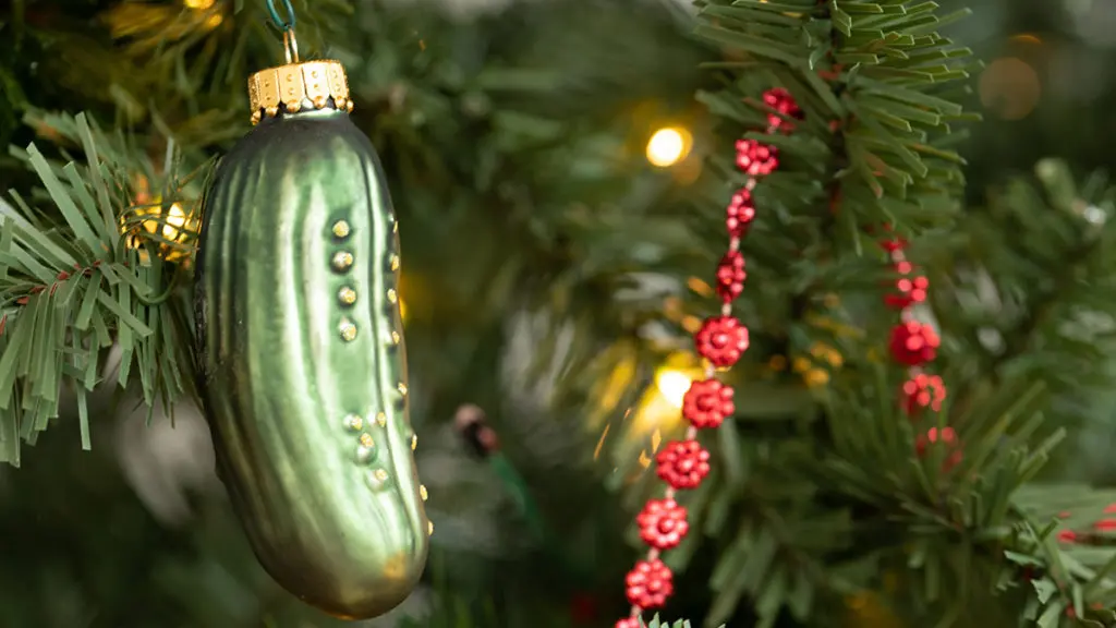 A photo of facts about Christmas with a closeup of a pickle ornament on a Christmas tree.