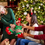 A photo of facts about Christmas with three people pulling at a Christmas gift while sitting on a couch and laughing