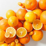 A photo of facts about oranges with a pile of whole and sliced oranges on a marble top table