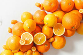A photo of facts about oranges with a pile of whole and sliced oranges on a marble top table