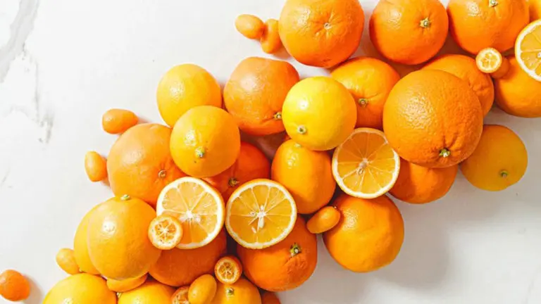 A photo of facts about oranges with a pile of whole and sliced oranges on a marble top table