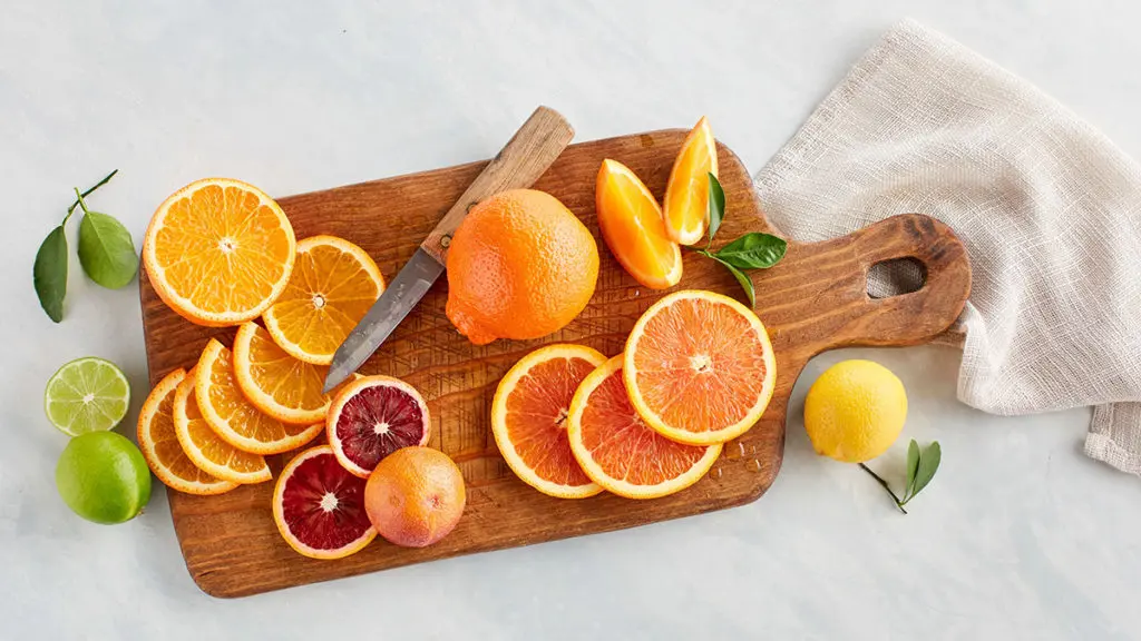 A photo of facts about oranges with a cutting board holding a knife and several slices of oranges