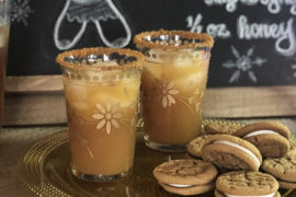 A photo of a craft cocktail with a plate of cookies in front