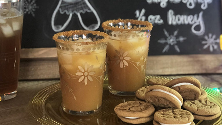 A photo of a craft cocktail with a plate of cookies in front