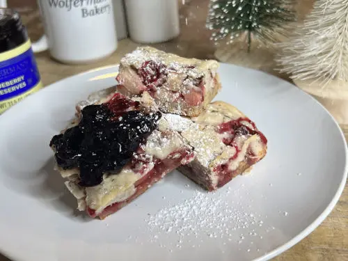 A photo of cobbler on a plate surrounded by a jar of preserves and a mug