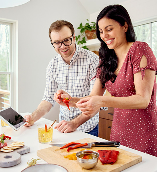 A photo of holiday gifts for employees with a man and a woman making a charcuterie board together.