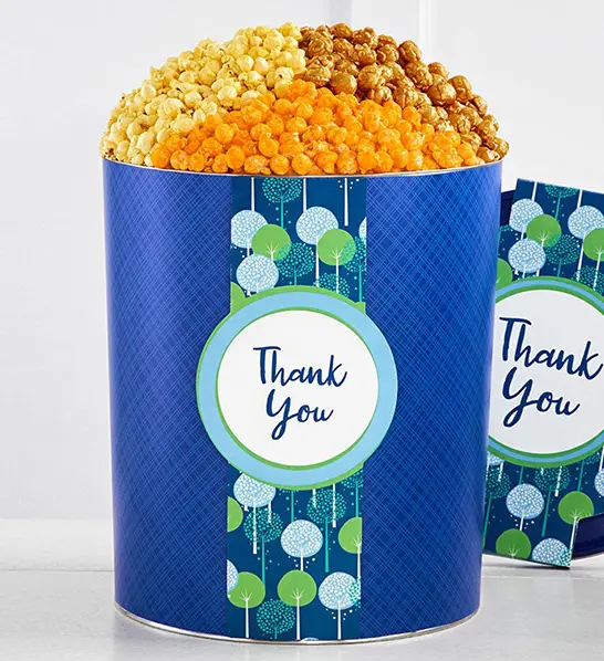 A photo of holiday gifts for employees with a tin of popcorn decorated with the words "thank you."