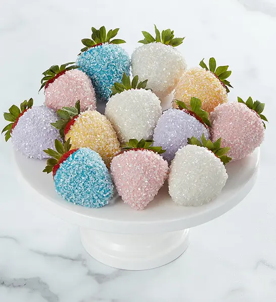 A photo of holiday gifts for employees with a plate of chocolate covered strawberries decorated with sparkles.