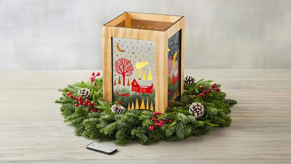 A photo of a holiday lantern surrounded by a Christmas wreath