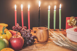 How to celebrate Kwanzaa with a candles, fruit and presents.