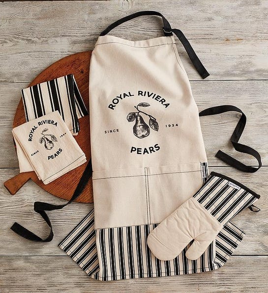 A photo of last minute gifts with an apron, an oven mitt and two kitchen towels lying on a wood floor.