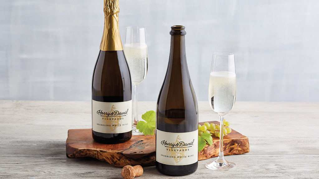 A photo of sparkling wine with two bottles of wine next to two full glasses of wine.