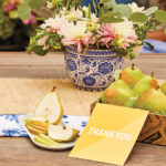 A photo of what to write in a thank you card with a box of pears with a thank you note in front and a plate of sliced pears