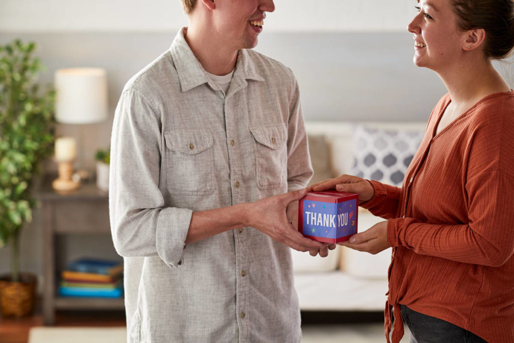 A photo of what to write in a thank-you card with a man giving a woman a gift.