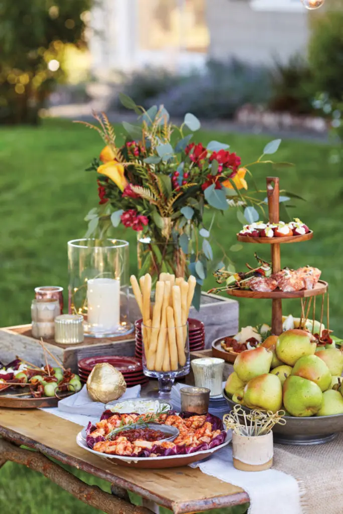 A photo of birthday party trends with a photo of a table stacked with appetizers outside