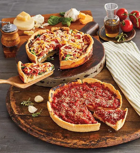 A photo of comfort foods with two deep dish pizzas on two cutting boards with ingredients for said pizzas surrounding them