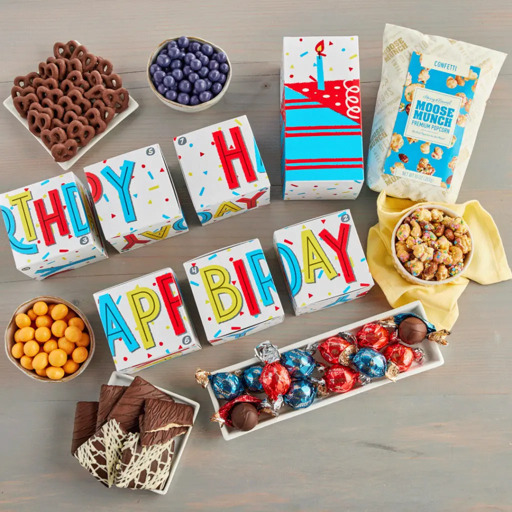 A photo of February birthday with an assortment of boxes wrapped in birthday wrapping paper surrounded by bowls of chocolate and other sweets.