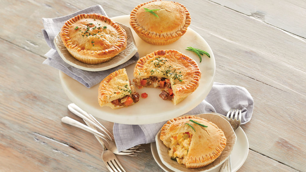 A photo of food trends with four pot pies arrayed on two plates with one of the pot pies sliced into