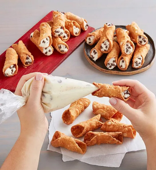 Gifts for couples with a pair of hands holding a frosting bag filling an empty cannoli.