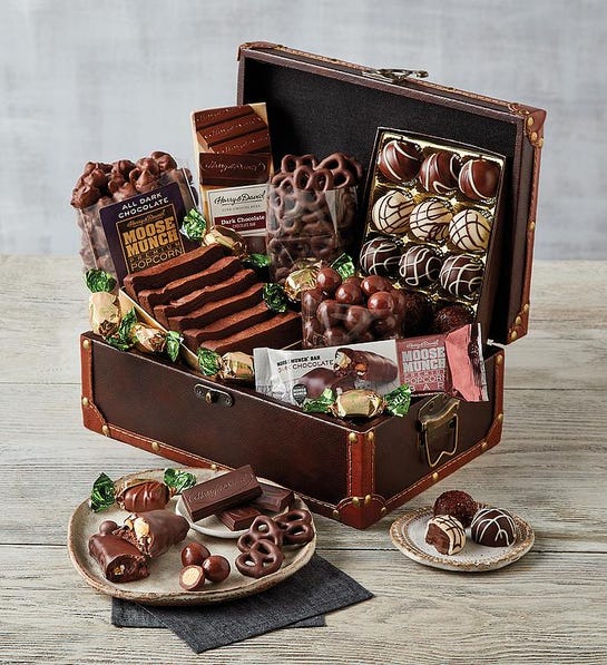A photo of gifts for couples with a chest of chocolate cake, truffles, cookies, and other chocolate delights.
