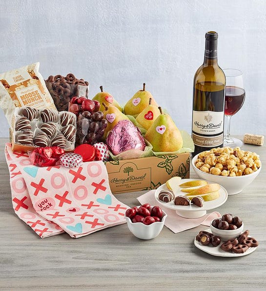 A photo of relationship length with a box full of pears, chocolate, and Moose Munch next to a bottle of wine and several bowls of the same ingredients.