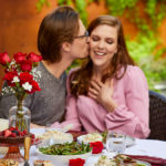 A photo of Valentine's Day Gifts for Her with a couple having a dinner outside with the man kissing the woman's cheek