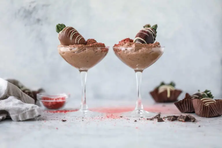 Chocolate mousse in two glasses topped with chocolate covered strawberries.