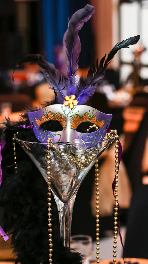 A photo of Mardi Gras with a martini glass holding beads and a Mardi Gras mask.